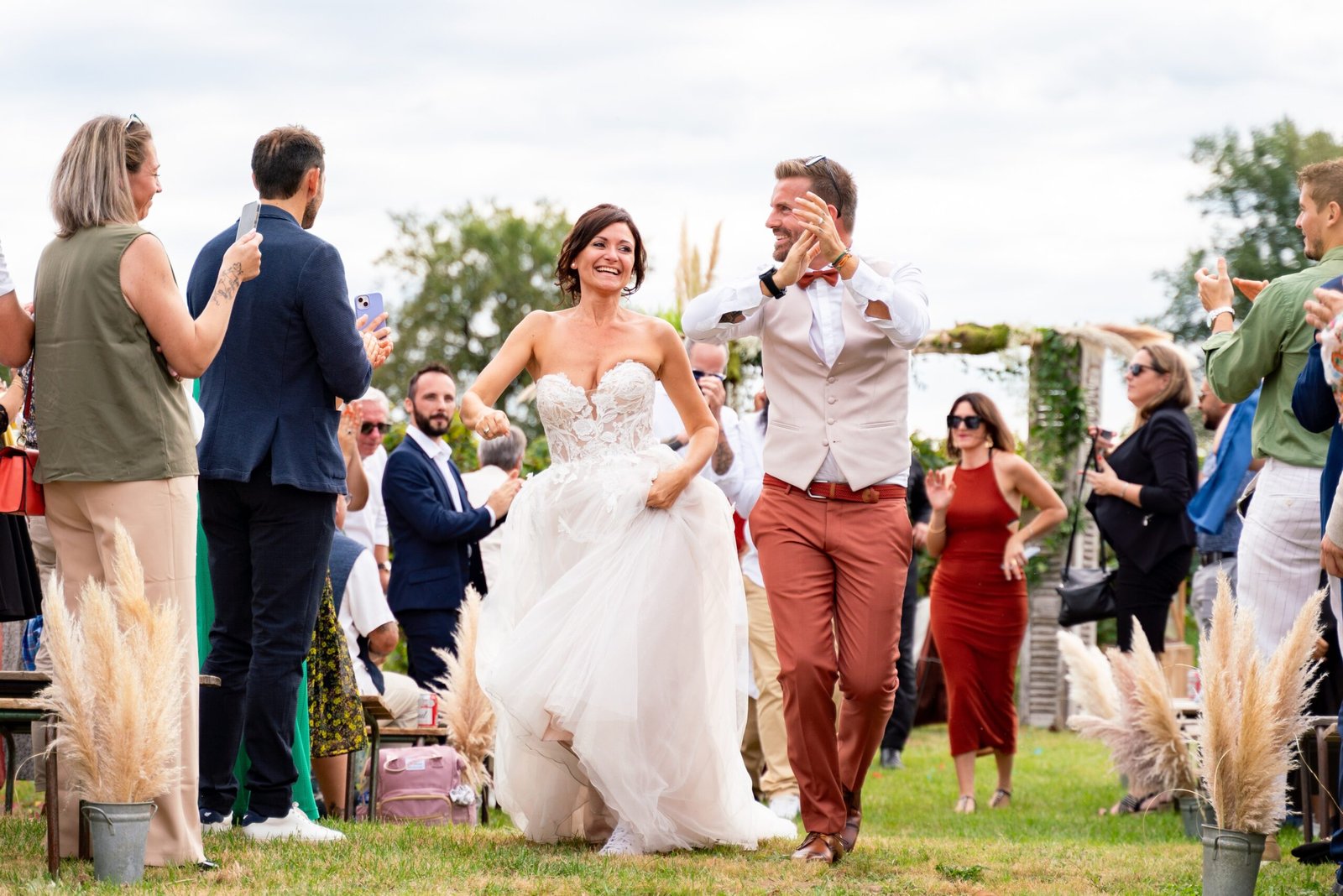 Mariés riant entourés d'invités en extérieur, mariage à Toulouse